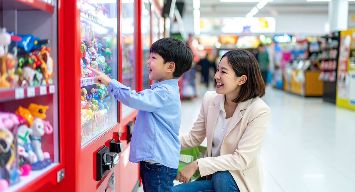 キャラクターを販売機で選んでいる男の子と見守っている母