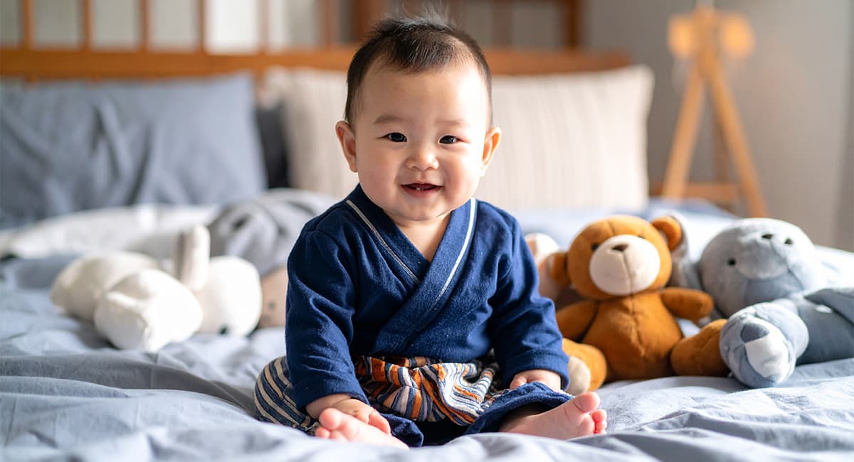 ベッドで沢山のぬいぐるみをそばで笑っている赤ちゃん